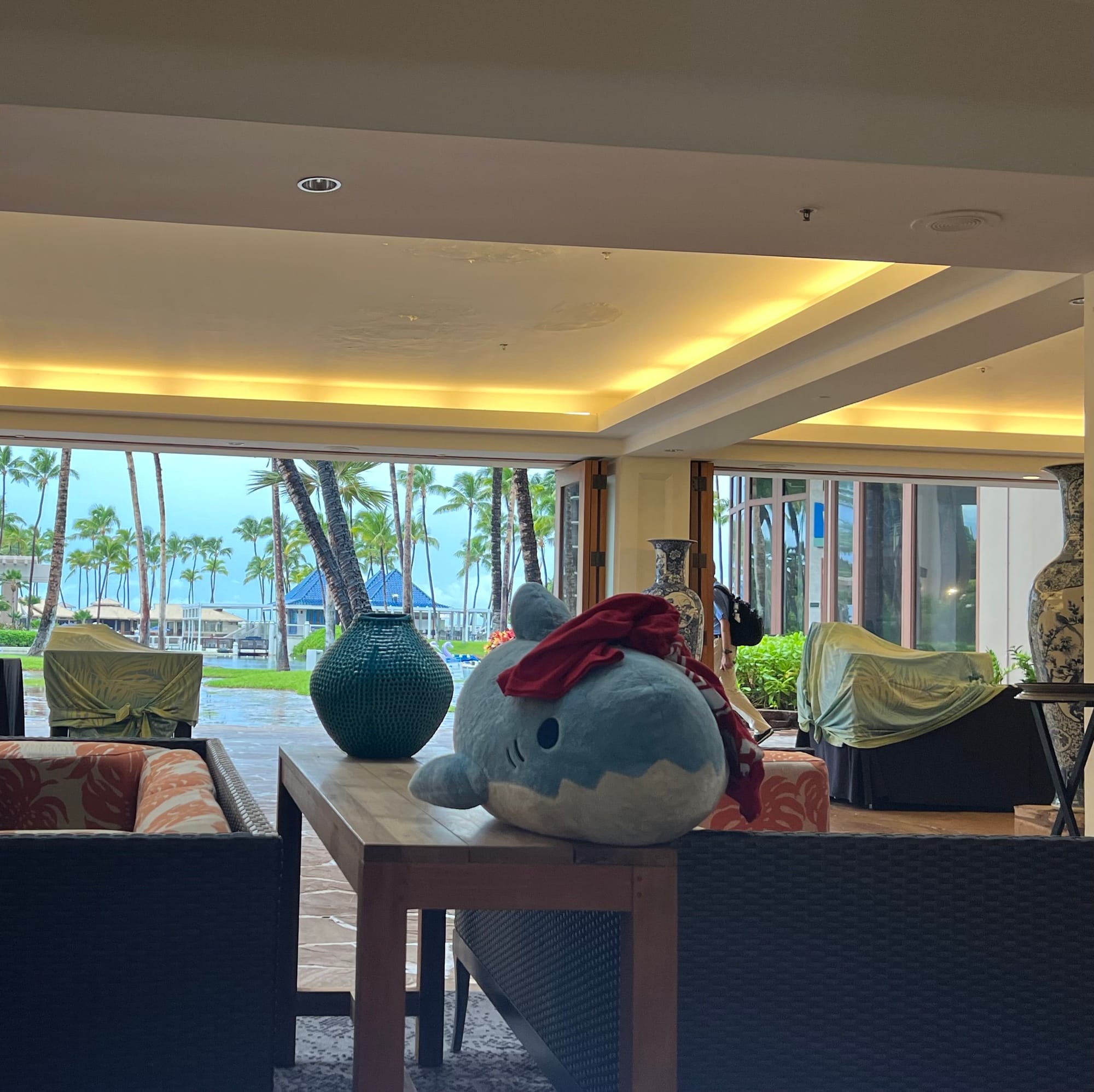 Stuffed shark resting on public table between two couches during conference.